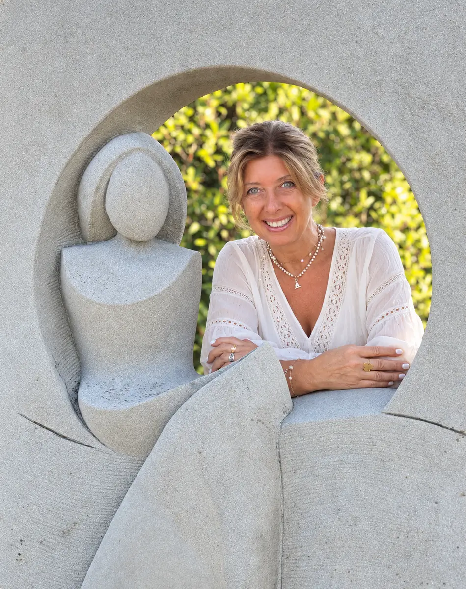 Nives Rota sorridente dentro il cerchio di una scultura in pietra
